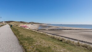 A coastal walkway leading to a sandy beach with a wooden fence separating the beach from the path. - Holiday Home Near the Beach Zoutelande (Zoutelande)