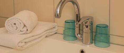 A bathroom with a white sink, a silver faucet, and three blue glass containers.