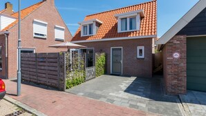 A residential property with a brick facade, a tiled roof, a gated entrance, and a paved driveway. - Holiday Home Near the Beach Zoutelande (Zoutelande)