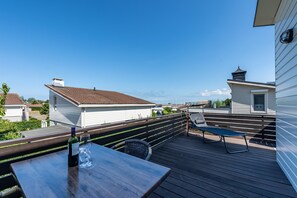 A deck with a table and chairs, overlooking a residential area with houses and a clear sky. - Bungalow Near Oosterschelde Beach (Kamperland)