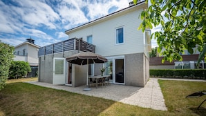 A modern house with a patio, a dining table, and an umbrella. - Bungalow Near Oosterschelde Beach (Kamperland)