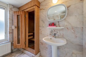 A bathroom with a wooden sauna door, a marble wall, a white sink, and a mirror. - Bungalow Near Oosterschelde Beach (Kamperland)