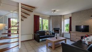 A modern living room with a staircase, a fireplace, a television, and a sofa. - Bungalow Near Oosterschelde Beach (Kamperland)