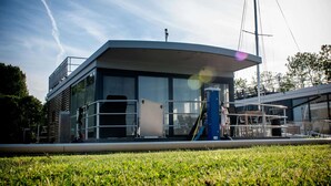 A modern building with large windows, a flat roof, and a small outdoor area with a metal railing. - Houseboat With Stunning Views (Offingawier)