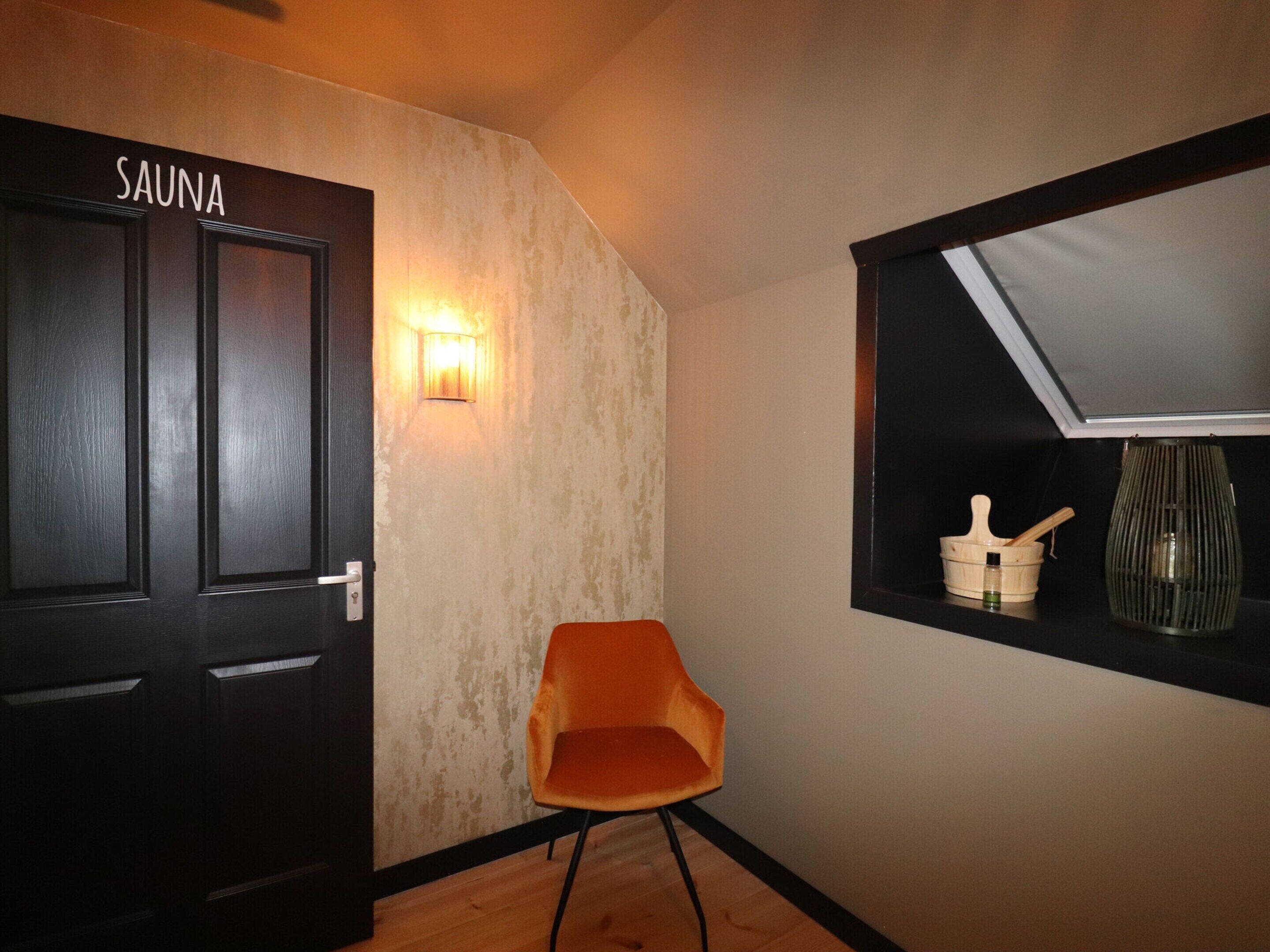 Una habitación con puerta de sauna, una lámpara de pared, ventanal con vistas y una silla.