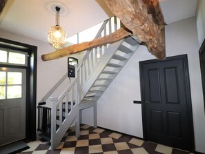 A staircase with a wooden beam, a chandelier, and a checkered floor. - Apartment in Netherlands Near Nature Trails (Dalerveen)