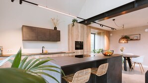 Una cocina moderna con una isla grande, taburetes de bar y un comedor con mesa y sillas.
