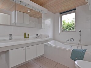 A modern bathroom with a white sink, vanity, and bathtub. - Modern Furnished Detached Bungalow, Located on the Marina (Kamperland)