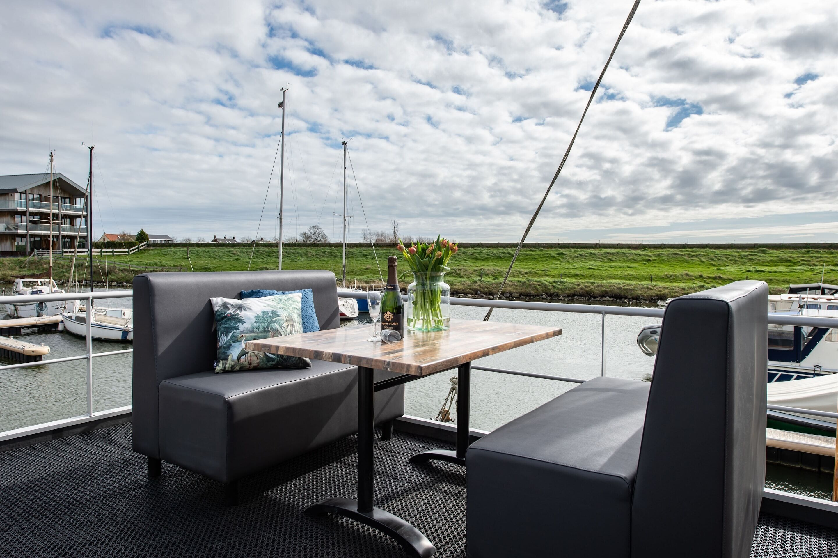 A deck with a table, two sofas, and a vase with flowers.