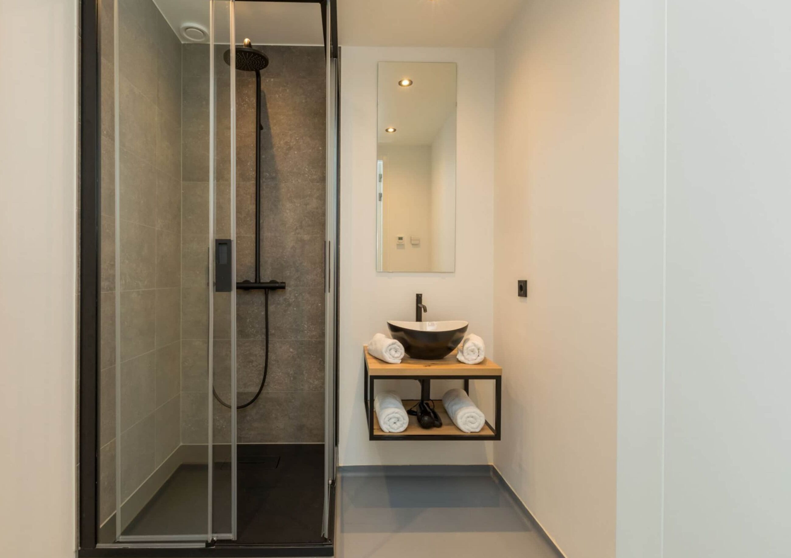 A modern bathroom with a glass-enclosed shower, a vessel sink, and a mirror above it.
