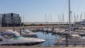 A marina with boats docked, a modern building, and a clear sky. - Apartment in Sint-annaland With Water Views (Sint-Annaland)