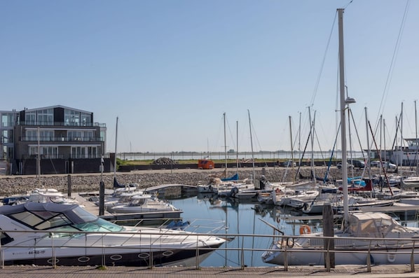 Un port de plaisance avec des bateaux amarrés, un bâtiment moderne et un ciel dégagé.