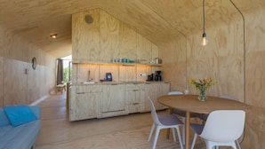 Una cocina moderna con armarios de madera, un comedor con una mesa redonda y sillas, y un sofá azul.