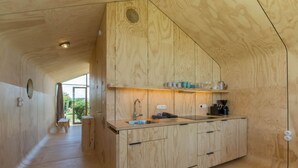 Interior de madera con área de cocina, que incluye un lavamanos, armarios y una ventana.