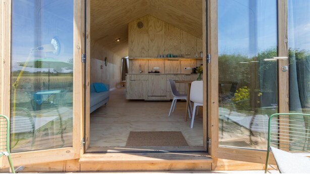 Interior de madera con cocina, comedor y sofá.
