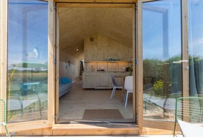 A wooden interior with a kitchen, dining area, and a sofa. - Tiny House in Zeeland Near Oranjezon Dunes (Vrouwenpolder)