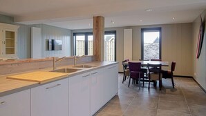 A modern kitchen with white cabinets, a wooden countertop, and a dining area with a table and chairs. - Attractive Holiday Home in Callantsoog With Fenced Garden (Callantsoog)