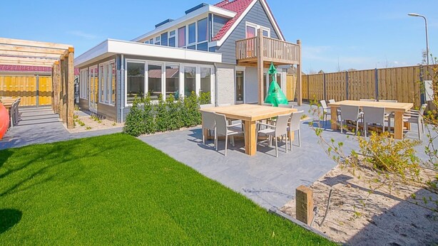 A modern house with a balcony, a patio with a table and chairs, and a well-maintained lawn. - Attractive Holiday Home in Callantsoog With Fenced Garden (Callantsoog)