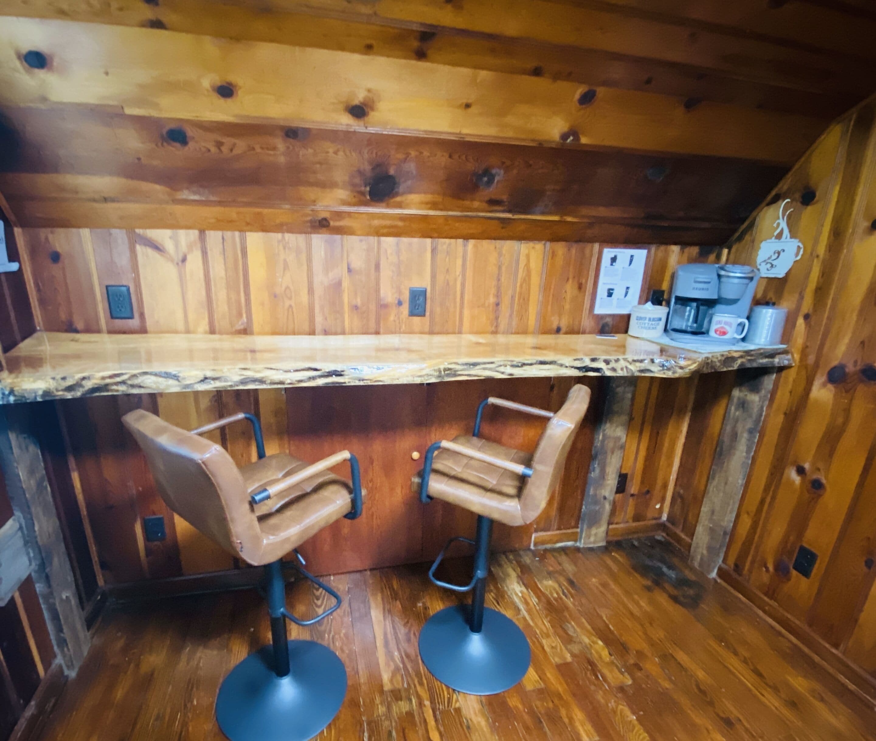 A wooden interior with a bar area featuring two stools and a countertop.
