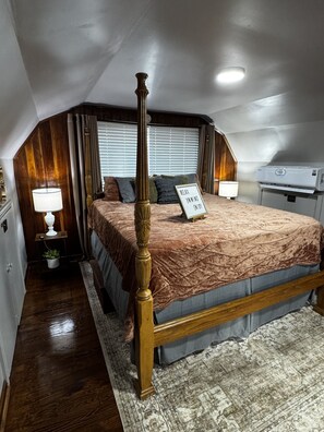 Ein Schlafzimmer mit Himmelbett, einem Schild mit der Aufschrift 'RELAX, UNWIND, ENJOY', Deckenventilator und einem großen Fenster mit Jalousien.