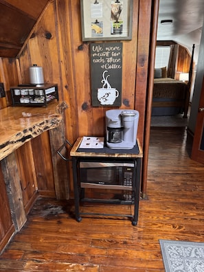 Et træbeklædt interiør med kaffeområde, inklusive en Keurig-maskine og en tavle.