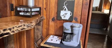 A wooden interior with a coffee station featuring a Keurig machine, a framed picture with cats, and a sign with a coffee cup.
