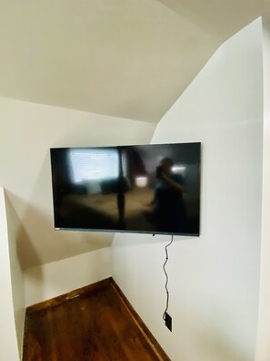 Un téléviseur à écran plat fixé au mur blanc d’une pièce, avec un meuble en bois placé en dessous.