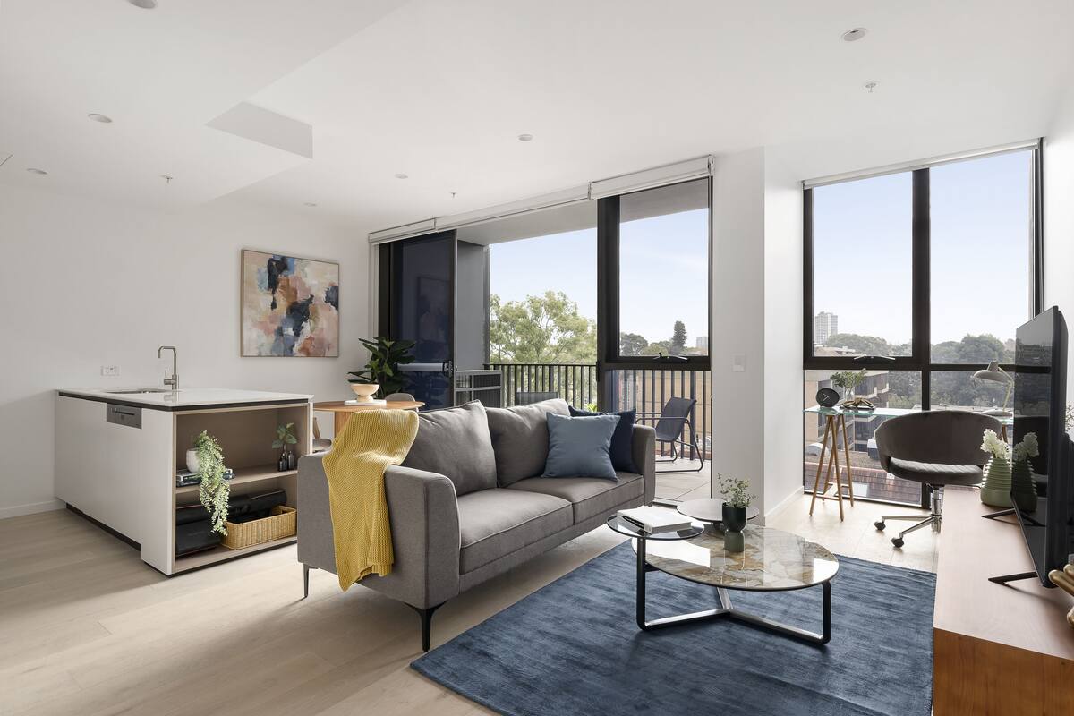 A modern living room with a sofa, coffee table, and a view of the city through large windows.