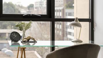 Une pièce moderne avec une table en verre, une horloge, une lampe et une chaise.