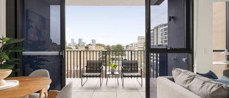 Un apartamento moderno con balcón, zona de comedor y sofá.