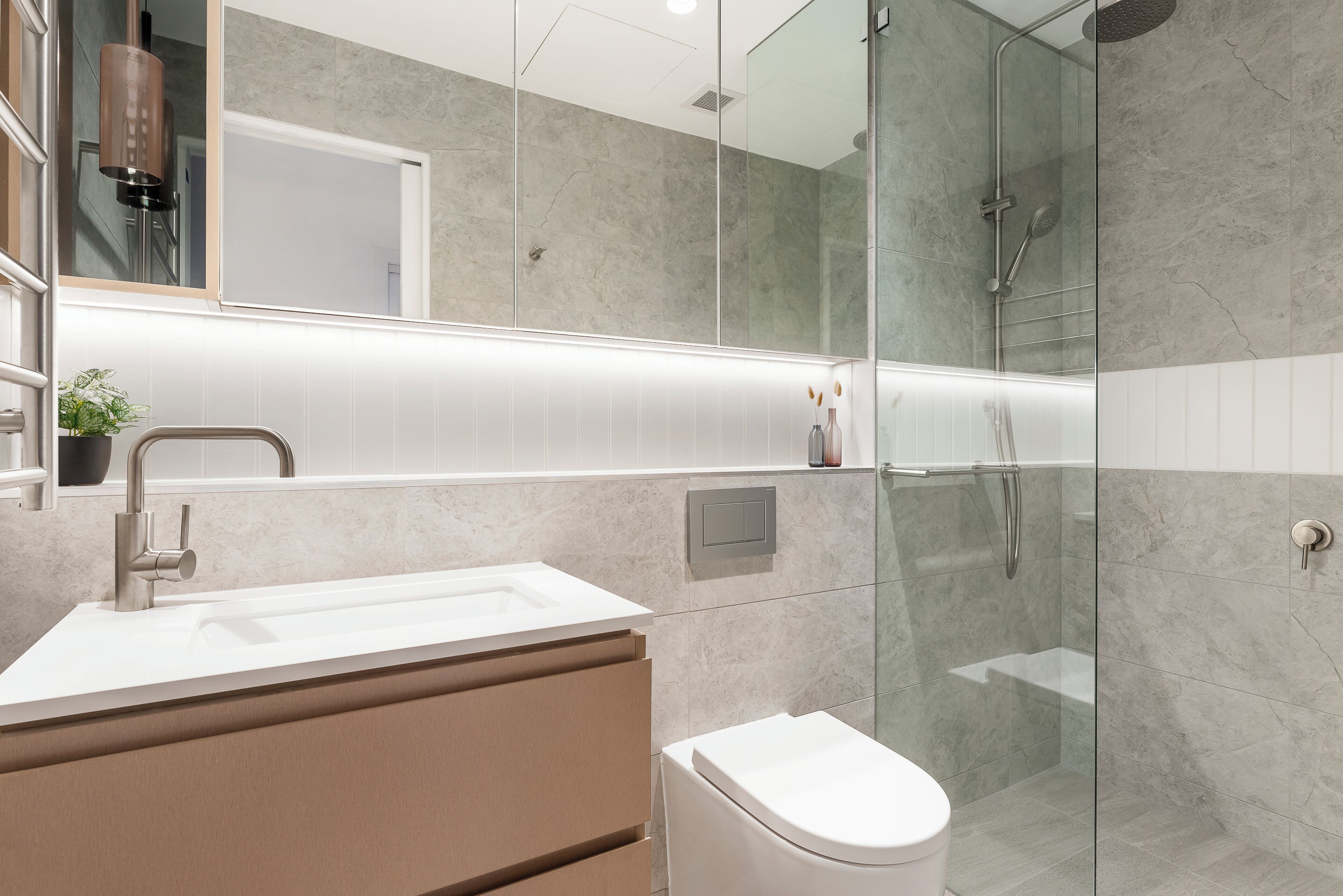 Une salle de bain moderne avec une douche à parois de verre, un lavabo blanc et un meuble-lavabo beige.