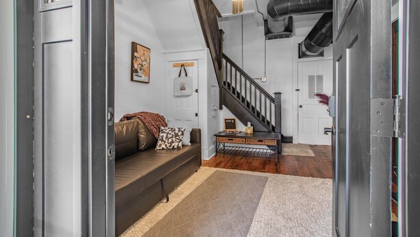A modern living room with a dark leather sofa, a wooden coffee table, a staircase, and a ceiling fan. - Gorgeous New Remodel - Close To It Everything! (Indianapolis)