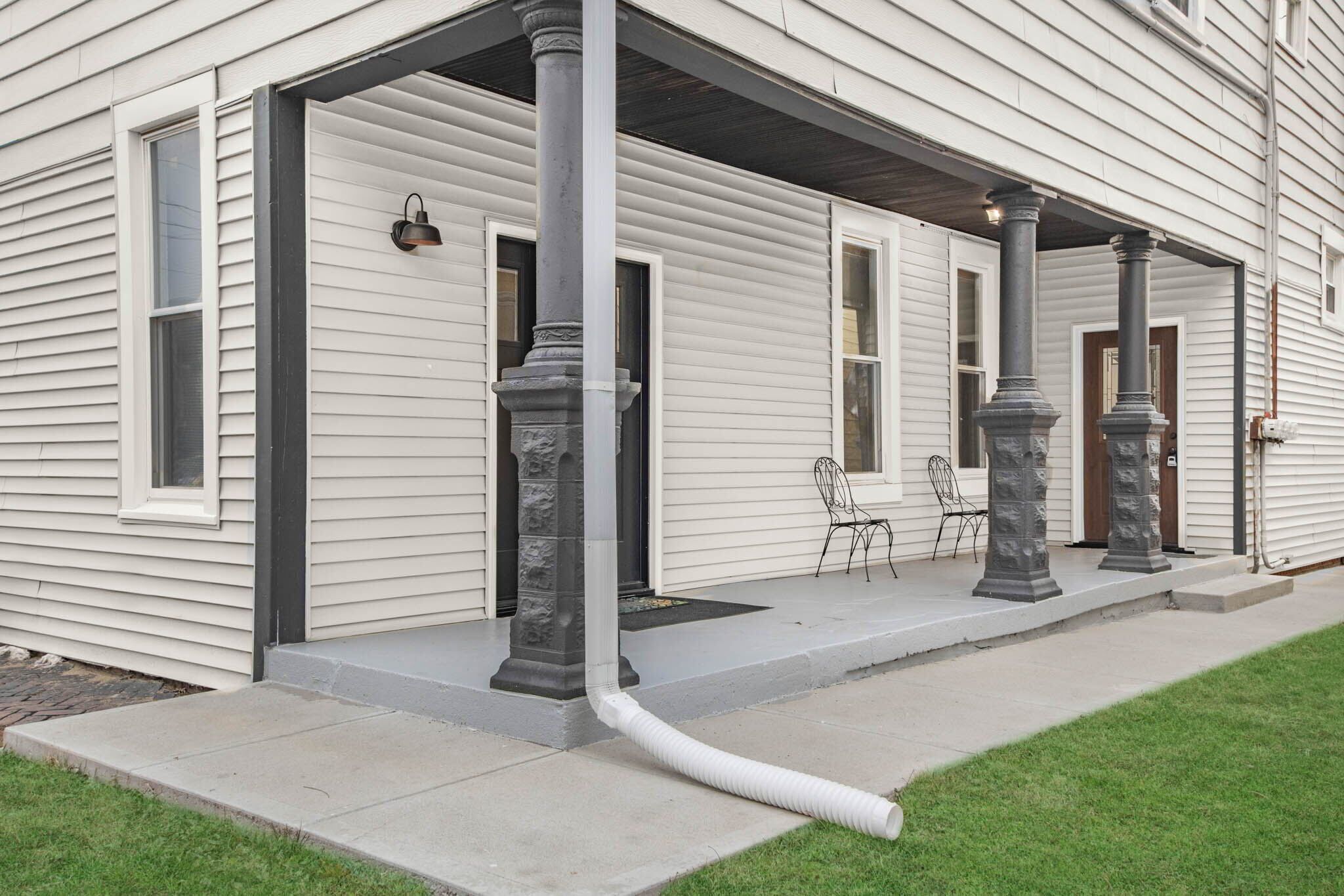 A house with a covered porch, stone columns, and a visible water line.