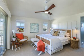 Un dormitorio amplio con una cama grande, ventilador de techo y vistas al exterior.