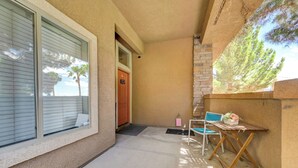 A building with a door, a window, a small table with chairs, and a view of trees. - Gated Dual Master Suites with Office and Dog Park (Las Vegas)