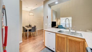 A modern kitchen with a dishwasher, wooden cabinets, and a large window with blinds. - Gated Dual Master Suites with Office and Dog Park (Las Vegas)