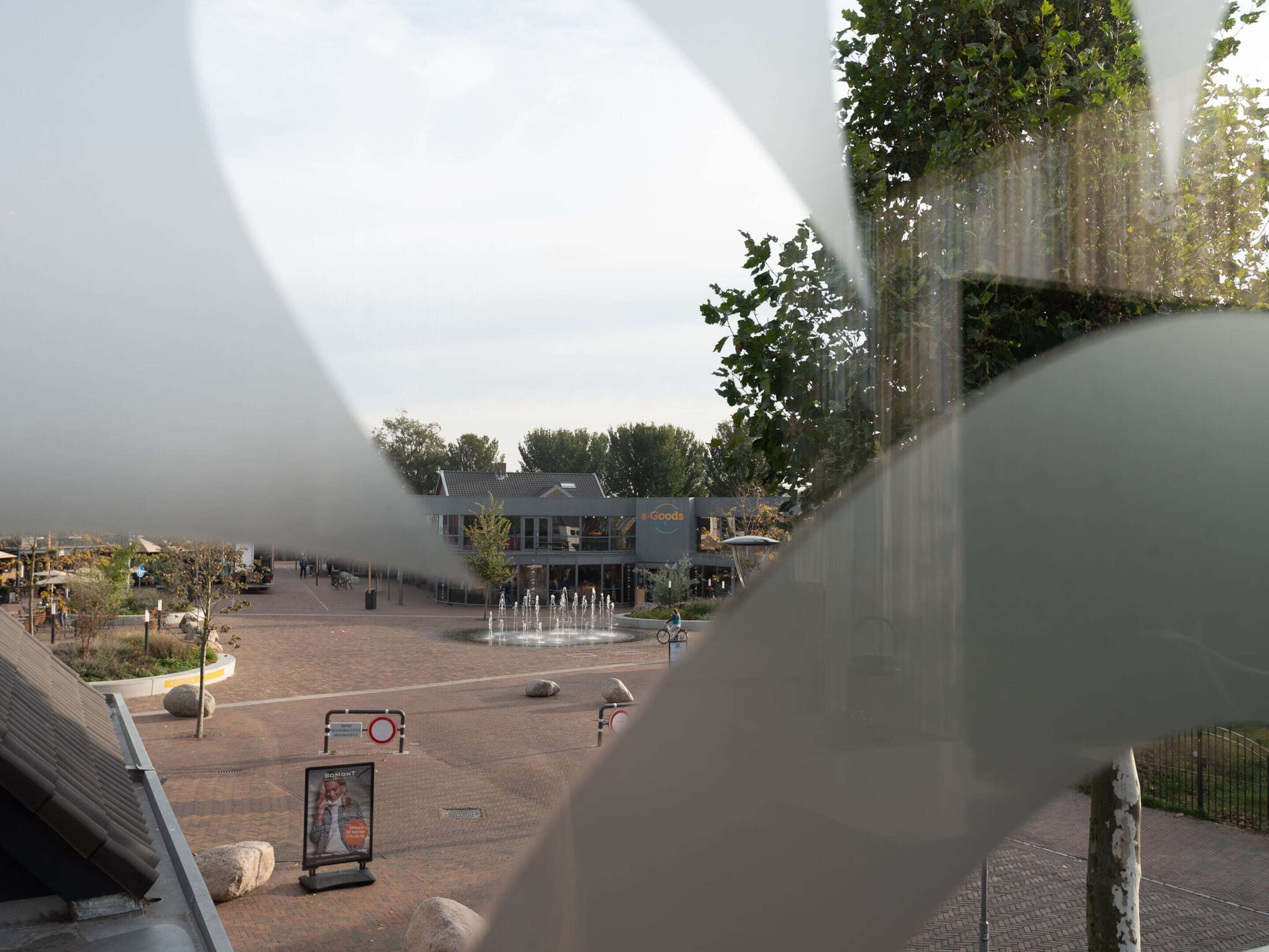A public square with a fountain, a building labeled 'S Goods', and a sign for 'Bombt'.