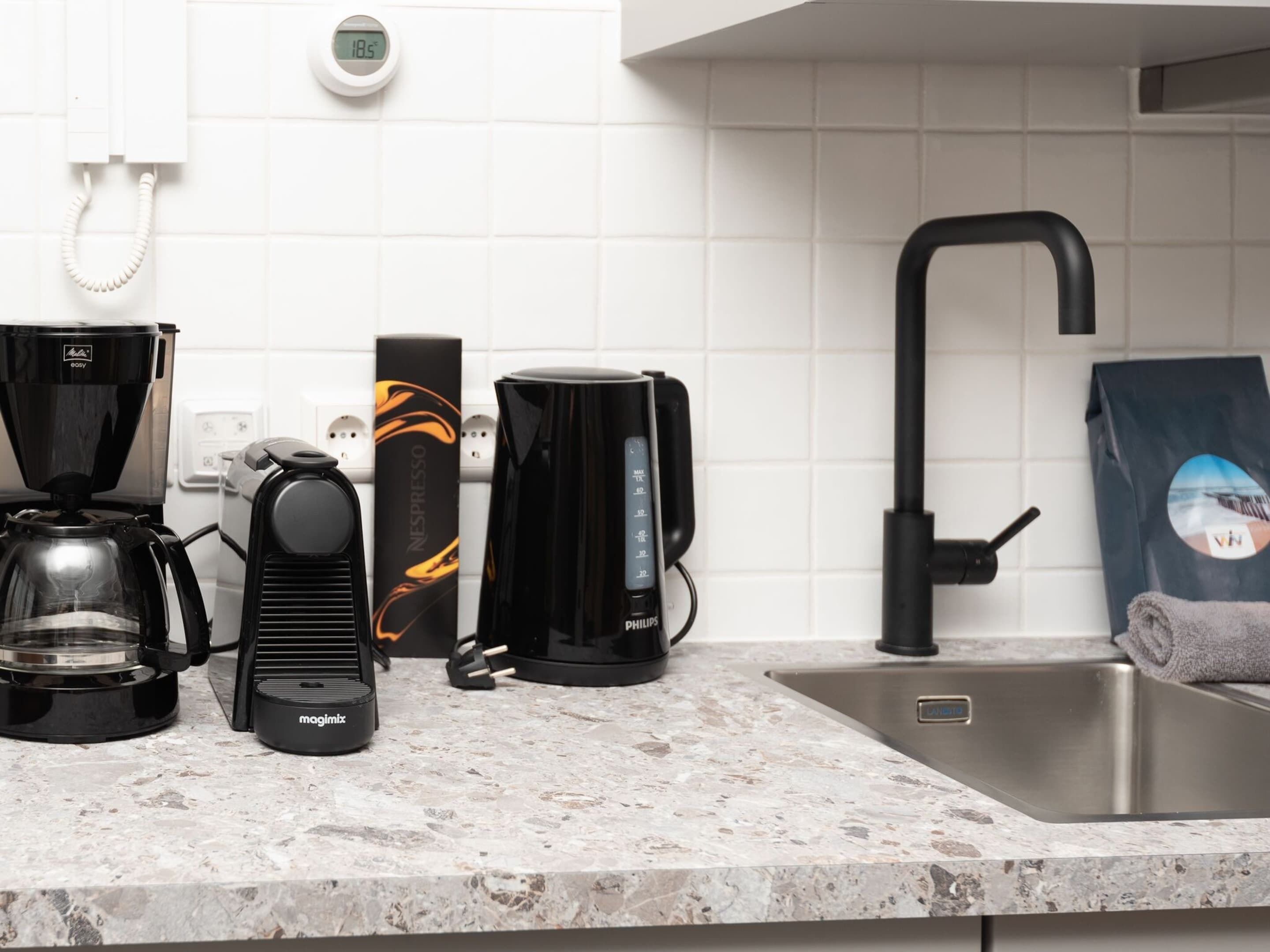 A kitchen with a coffee maker, espresso machine, and a bag of coffee.