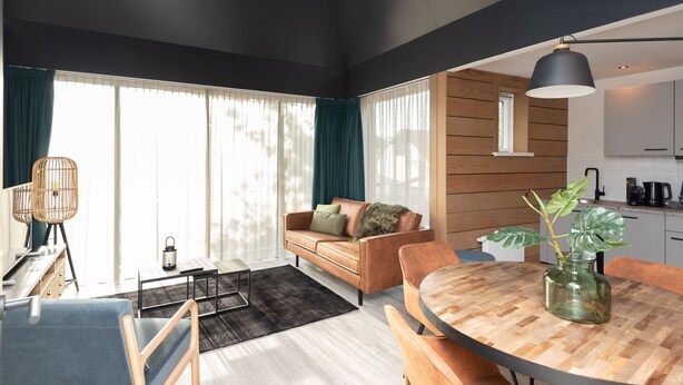 A modern living room with a sofa, coffee table, and dining area. - Studio in Domburg Near Beach and Nature Reserve (Renesse)