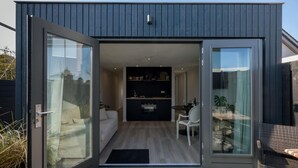 Ein moderner, kompakter Wohnraum mit Glastürschieberausgang, einer Küchenzeile und einer Sitzecke mit Tisch und Stühlen.