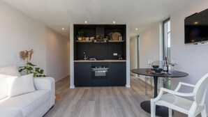 Eine moderne Küche mit schwarzen Schränken, einem eingebauten Backofen und einem Essbereich mit einem runden Tisch und weißen Stühlen.
