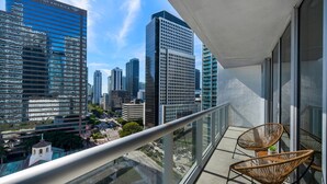 A balcony with wicker chairs and a view of a cityscape with modern buildings. - ICON W BRICKELL SPLENDID OCEAN VIEW 2BR/1BA #1709 (Miami)