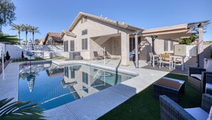 Un área de piscina con piscina cristalina, mobiliario exterior y un porche cubierto.