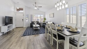 Una sala de estar moderna con comedor, paredes blancas y ventilador de techo.