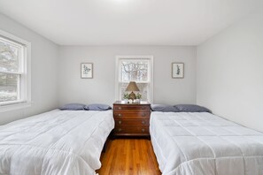 A bedroom with two beds, a wooden dresser, and two framed pictures on the walls. - The Sanctuary Downtown >5mi to Downtown & Union Park (Raleigh)