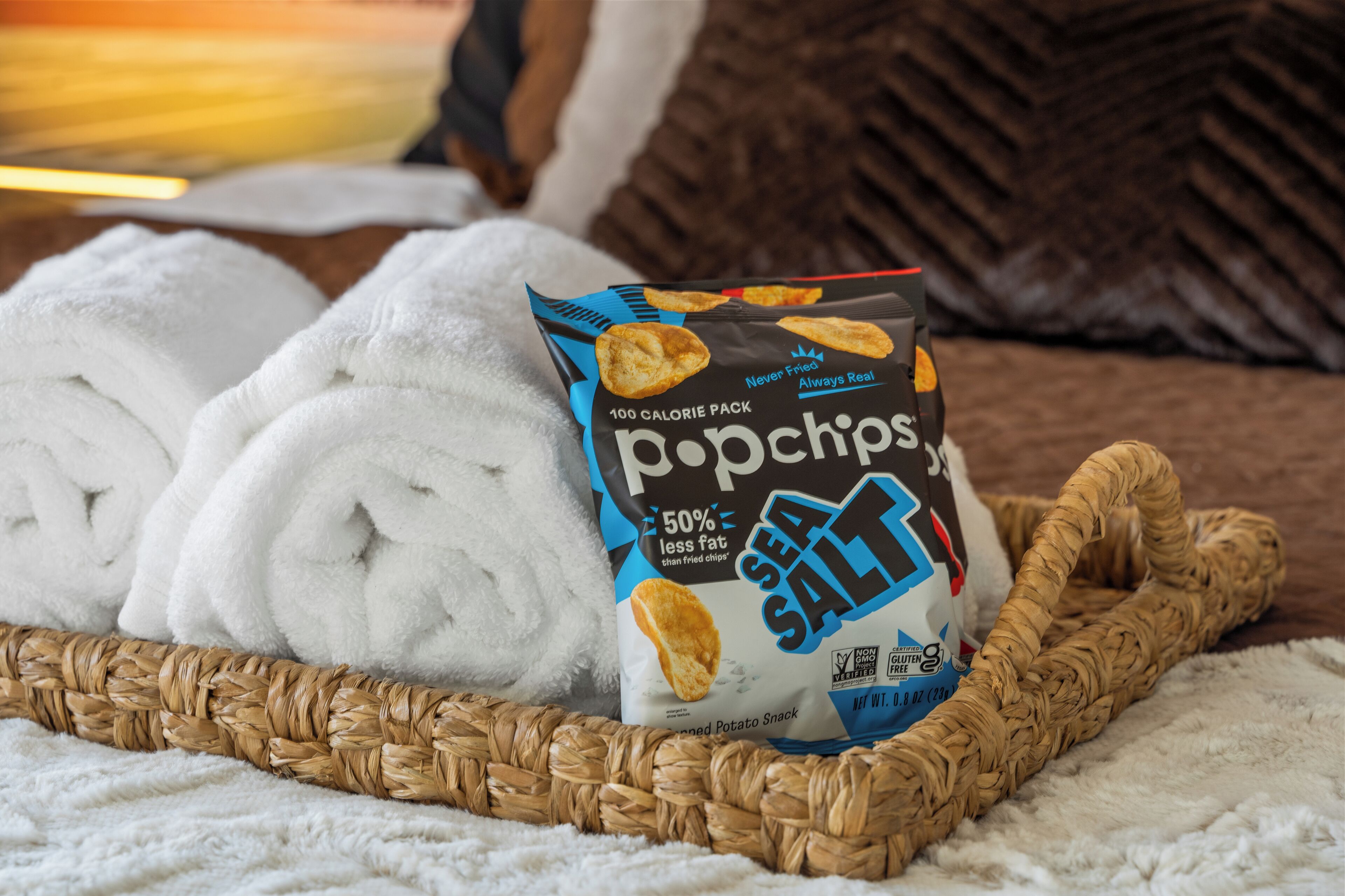 Eine Tüte Popcorn-Chips auf einem weißen Handtuch und ein geflochtener Korb.