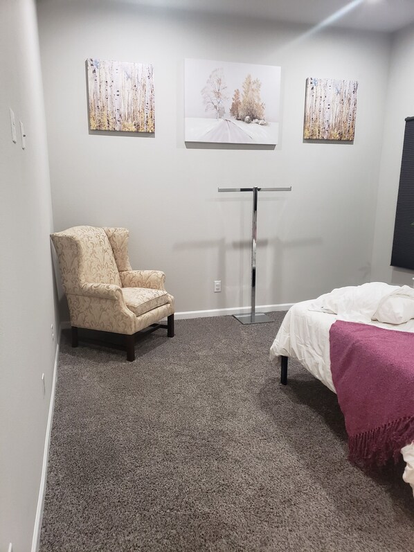 Een slaapkamer met een bed, een stoel en drie kunstwerken aan de muur.
