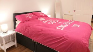 En seng med et pink sengetæppe og puder med teksten "Keep Calm and Snuggle Up".