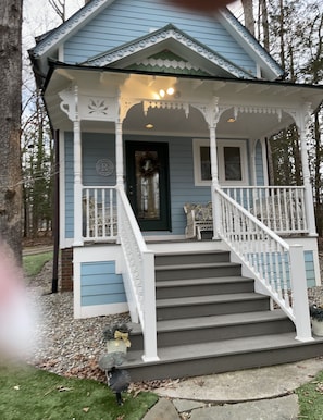 Ein kleines, eingeschossiges Haus mit einer Veranda, einer Treppe und einer Haustür.