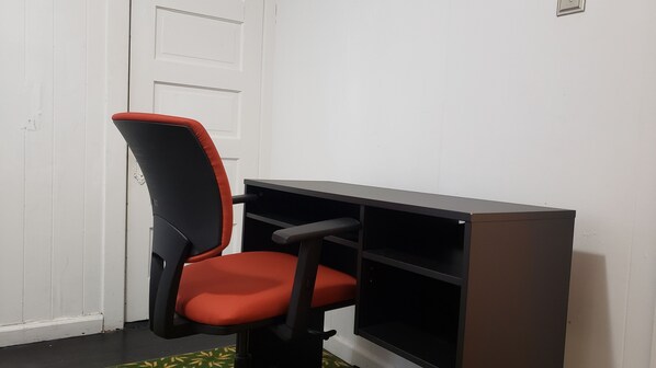 A corner office with a red and black chair, a desk, and a white door.